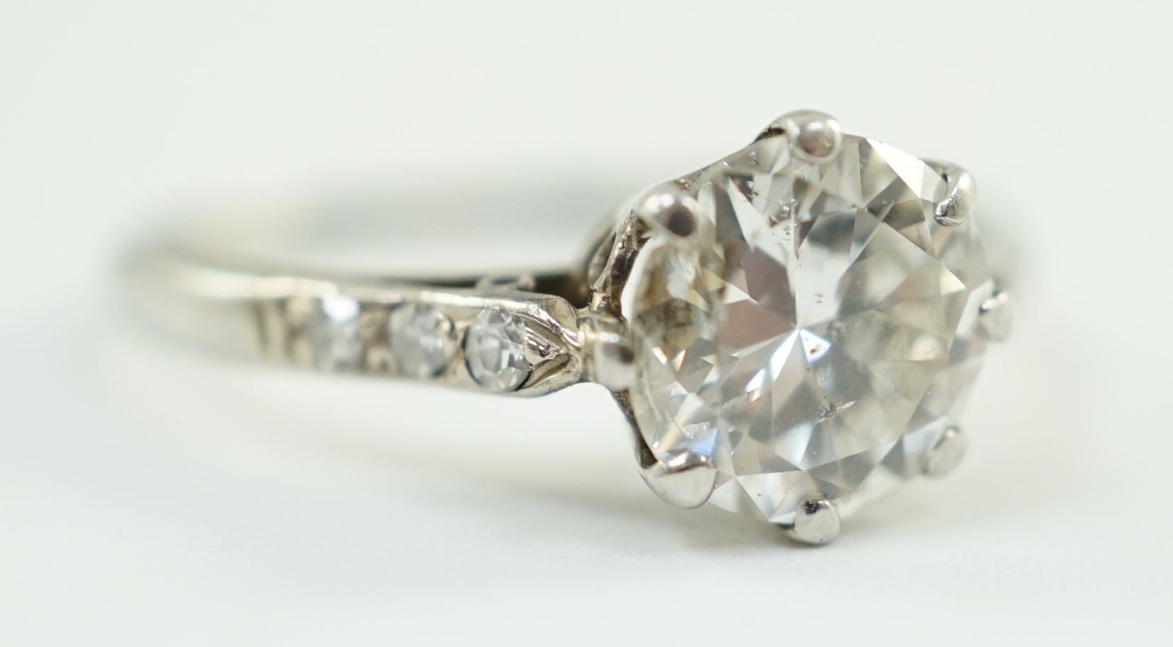 A platinum and single stone diamond ring, with diamond set shoulders